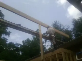 Carpenter setting a ridge beam over a new addition frame — Ice Dam Removal by Roofing Brothers in Oak Hill