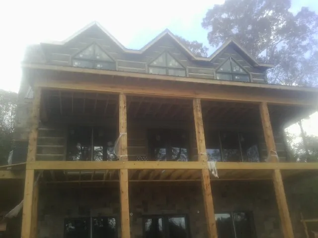 Dormers and porch framing on a large log home under construction — Roof Coating work by our crew in Oak Hill