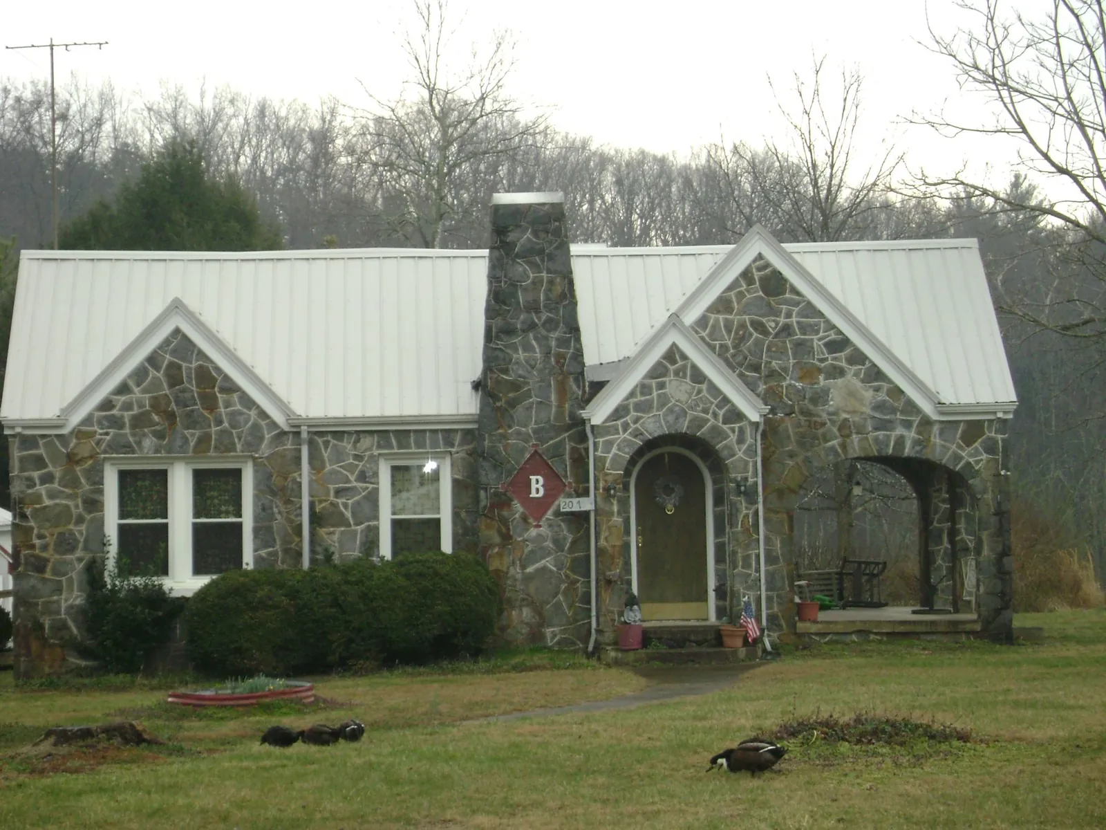White metal roof on a stone cottage with steep gables in Oak Hill