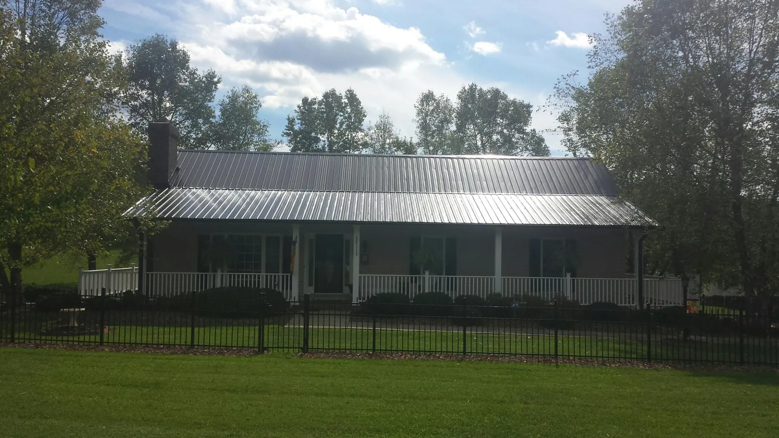 Gray metal roof on a brick ranch with a full width front porch — Gutter Guard Installation work by our crew in Oak Hill
