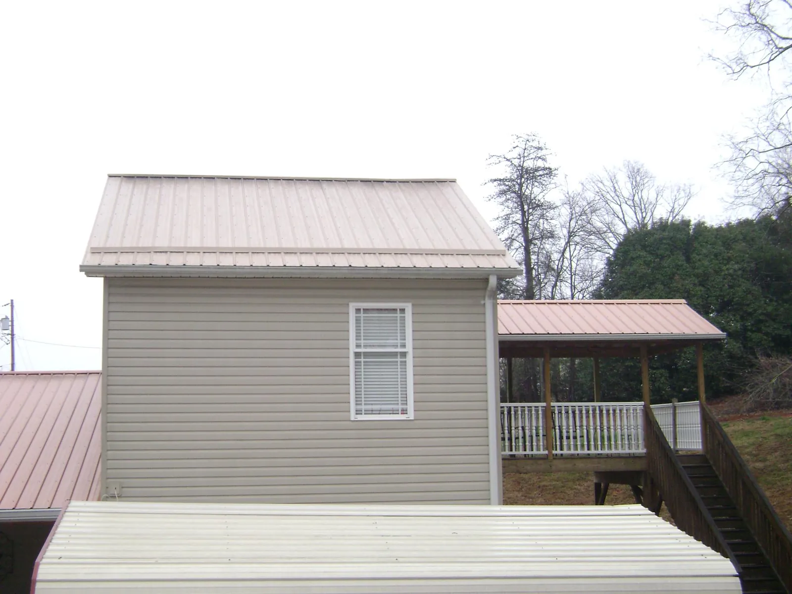 Tan metal roofs on a two story addition and attached porch, from a Roof Replacement job in Oak Hill